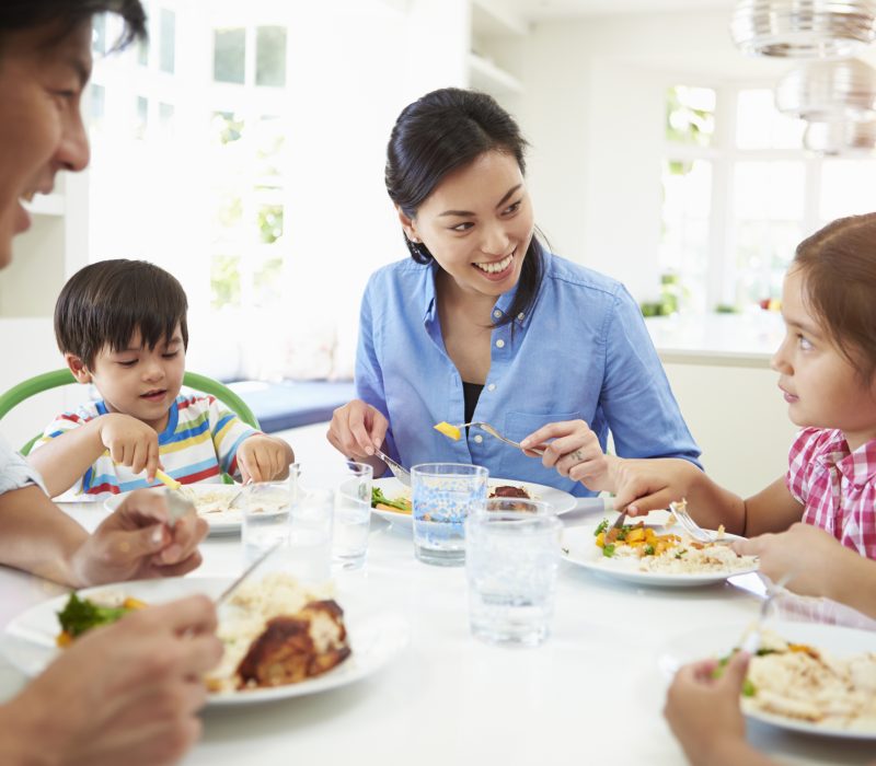 Asian Family Sitting At Table Eating Meal Together