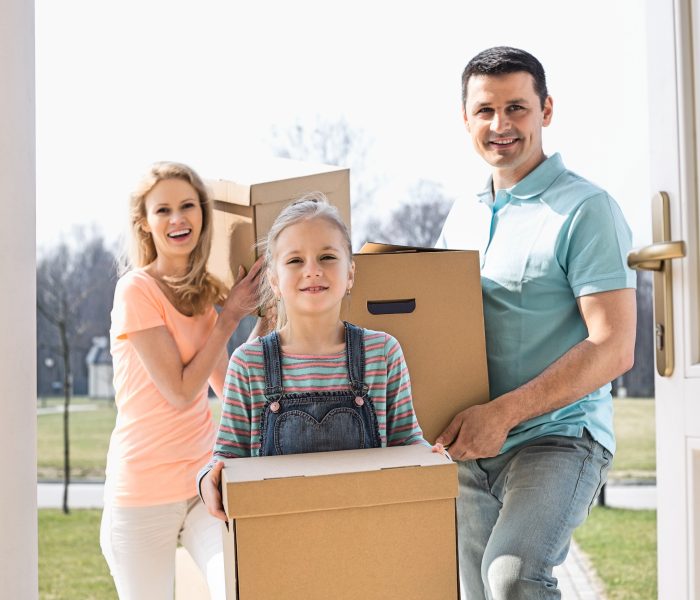 Happy family with cardboard boxes entering new home